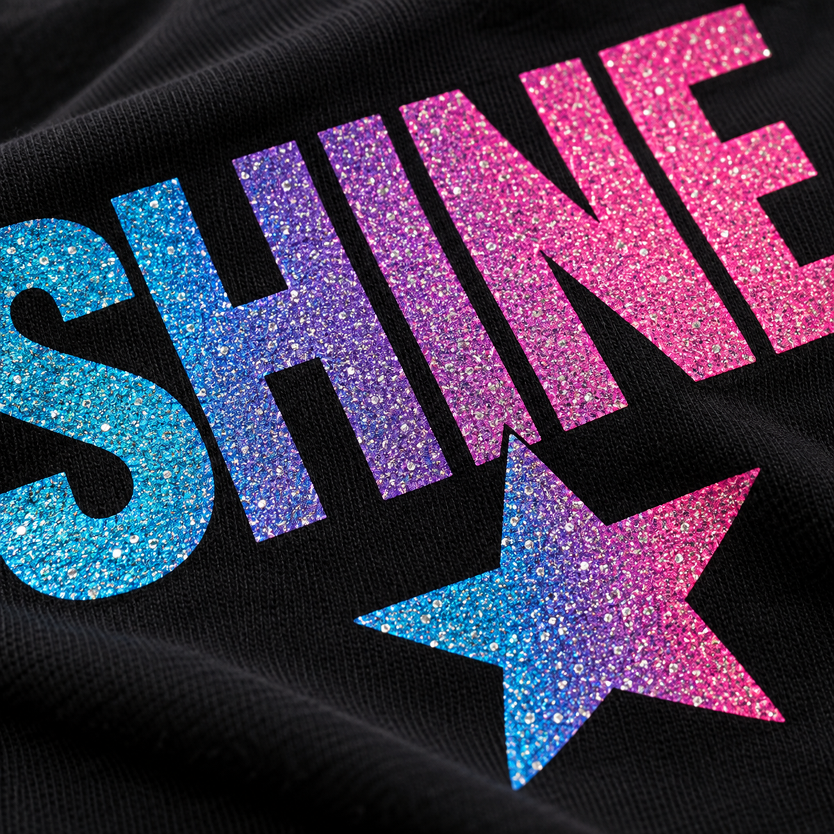 Illustrative close-up of fine glitter DTF shimmer on black fabric; actual finish varies with artwork and lighting